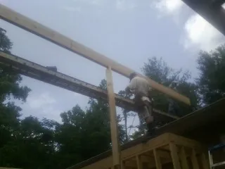 Carpenter setting a ridge beam over a new addition frame — Ice Dam Removal by Roofing Brothers in Monroe